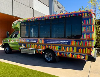 The Book Bus, viewed from its left side, parked outside the Advanced Learning Library
